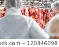 Butchers processing hanging beef carcasses in meat processing plant 120846098