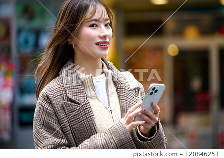 Young woman in winter clothes holding a smartphone 120846251
