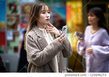 Young woman in winter clothes holding a smartphone 120846253