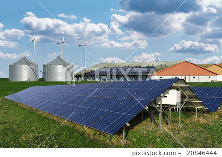 Modern farm using renewable energy. Solar panels with silos in the background 120846444