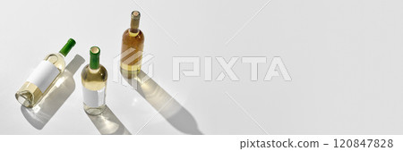 Banner. Three white wine bottles with white label, mockup arranged with green caps. Negative space for to insert text, brand name. 120847828