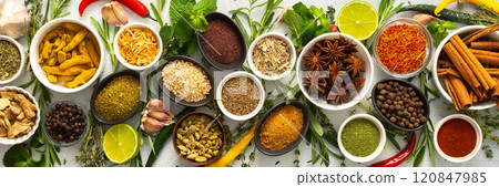 Assorted cooking spices and herbs arranged on a gray surface, featuring natural tones that add depth and aroma to any meal, banner 120847985