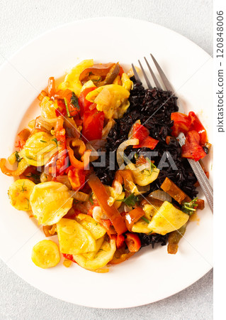 This wholesome breakfast includes black rice with stewed vegetables, stewed tomatoes, zucchini, peppers and onions top view 120848006