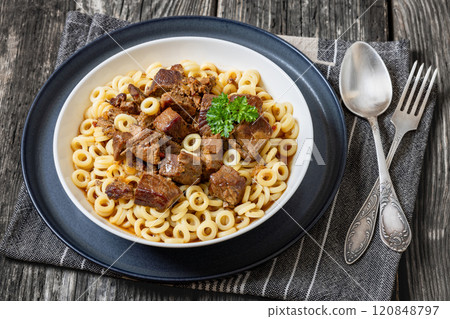 pasta rings topped with braised meat in bowl pasta rings topped with braised meat in bowl 120848797