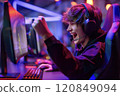 Young gamer enthusiastically celebrating a victory while playing computer games in a gaming club 120849094
