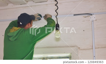 An electrician conducts wiring in a wooden house. An electrician conducts wiring in a wooden house. 120849363