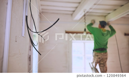 An electrician conducts wiring in a wooden house. An electrician conducts wiring in a wooden house. 120849364