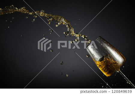 Glass and white wine splash on a black background. Glass and white wine splash on a black background. 120849639