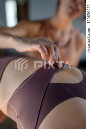 Pilates trainer touching the spine on the woman's back gently to focus attention on body movement. Pilates trainer touching the spine on the woman's back gently to focus attention on body movement. 120850031
