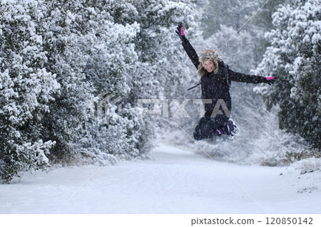 Young woman jumping in snow outdoor. 120850142