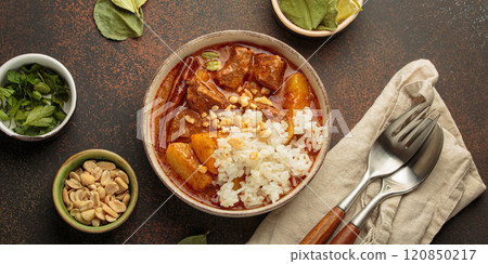 Delicious massaman curry with beef, potatoes, rice, and peanuts is served in bowl top view, Thai cuisine 120850217