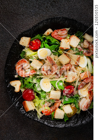 caesar salad with tiger prawns, shrimp salad, lettuce leaves, quail eggs, cherry tomatoes, parmesan cheese, on a black plate, caesar salad with tiger prawns, shrimp salad, lettuce leaves, quail eggs, cherry tomatoes, parmesan cheese, on a black plate, 120850535