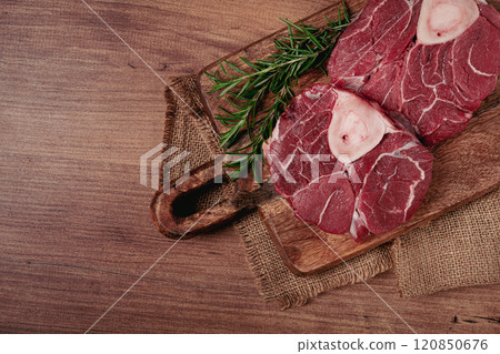 knuckle on the bone, raw meat for ossobuco, on a wooden chopping board, with a sprig of rosemary, and spices, top view, no people, 120850676