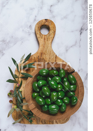 Halkidiki olives, classic Greek green olives, in a wooden bowl, on a cutting board, top view, without people, Halkidiki olives, classic Greek green olives, in a wooden bowl, on a cutting board, top view, without people, 120850678