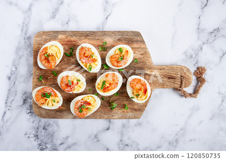 Boiled eggs stuffed with yolk and seasoned with mayonnaise, stuffed eggs with shrimp, on a wooden chopping board, selective focus, close-up, no people, Boiled eggs stuffed with yolk and seasoned with mayonnaise, stuffed eggs with shrimp, on a wooden chopping board, selective focus, close-up, no people, 120850735