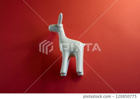 A beautifully stylized white animal figurine stands out vividly against a bright red background 120850775