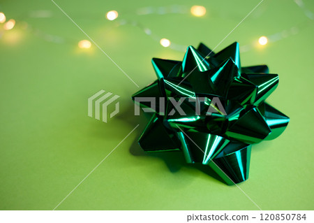 An Elegant Green Gift Bow beautifully placed on a Soft and Light Background that enhances its charm 120850784