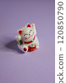 An Adorable Cute Maneki Neko Figurine Set Against a Bright Purple Background for a Charming Display 120850790