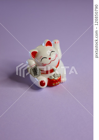 An Adorable Cute Maneki Neko Figurine Set Against a Bright Purple Background for a Charming Display An Adorable Cute Maneki Neko Figurine Set Against a Bright Purple Background for a Charming Display 120850790