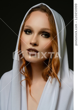 Elegant portrait of a woman wearing a white hooded garment in a studio setting Elegant portrait of a woman wearing a white hooded garment in a studio setting 120850999