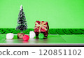 Small holiday decorations on a laptop keyboard with a green background during festive season preparations 120851102