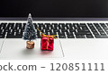 Miniature Christmas tree and gift resting on a laptop keyboard during the holiday season 120851111