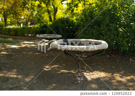 Black white rope circle swing seat at the playground close-up. Black net swing bench on a kids playground. Modern urban environment. 120852022