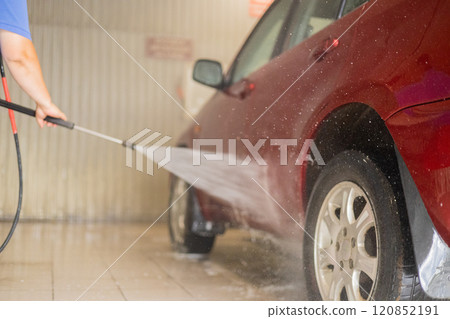 After washing, the man covers the car with protective wax. The driver washes the car after a long drive with foam and water. Self service car wash concept. After washing, the man covers the car with protective wax. The driver washes the car after a long drive with foam and water. Self service car wash concept. 120852191