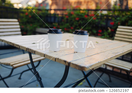 Cardboard takeaway coffee cup with plastic lid on wood table outdoors Cardboard takeaway coffee cup with plastic lid on wood table outdoors 120852197