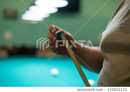 Close-up. A man's hand rubs the tip of a billiard cue with chalk for a more accurate shot. A man prepares to play billiards by rubbing his cue with chalk to prevent it from slipping. Close-up. A man's hand rubs the tip of a billiard cue with chalk for a more accurate shot. A man prepares to play billiards by rubbing his cue with chalk to prevent it from slipping. 120852210