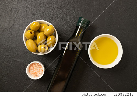 Olives and olive oil in bowl with bottle of olive oil on dark background. Mockup for package. Copy space. 120852213