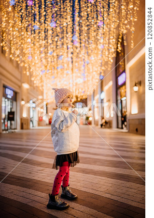 Child enjoying festive lights in a cheerful shopping area during the evening 120852844