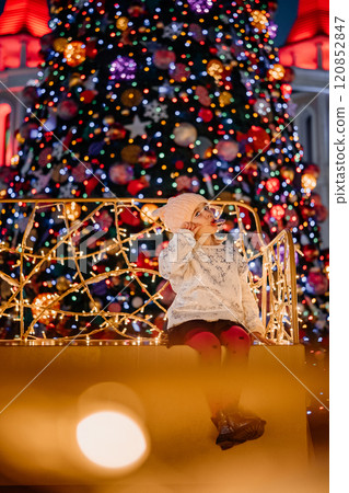 Child enjoying festive atmosphere near decorated Christmas tree at nighttime Child enjoying festive atmosphere near decorated Christmas tree at nighttime 120852847