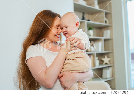 Happy family at home. Mother holding little toddler child daughter. Mom and baby girl relax playing having fun together at home. Mother hugs baby with love care. Mom of breast feeding baby 120852941