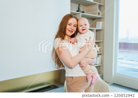 Happy family at home. Mother holding little toddler child daughter. Mom and baby girl relax playing having fun together at home. Mother hugs baby with love care. Mom of breast feeding baby 120852942