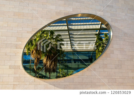 Futuristic landscape, Modern building architecture in the Champalimaud Foundation, oval windows in the wall leading to a garden with palm trees 120853029