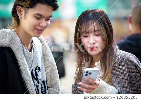 A young couple operating a smartphone in the city A young couple operating a smartphone in the city 120853203