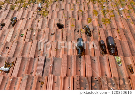 broken bottles of wine and beer on the tiled roof of a building, rubbish in public places, environmental pollution 120853616