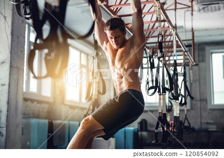 An athlete trains at a modern gym using TRX suspension equipment for better workouts 120854092