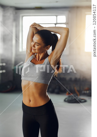 A fit, young woman is stretching in a contemporary gym setting with energy and focus A fit, young woman is stretching in a contemporary gym setting with energy and focus 120854117