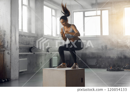 A Dynamic Woman Engaging in the Box Jump Exercise Within a Gym Environment Setting 120854133