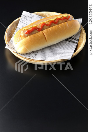 Hot dog with ketchup and mustard photographed against a black background 120855448