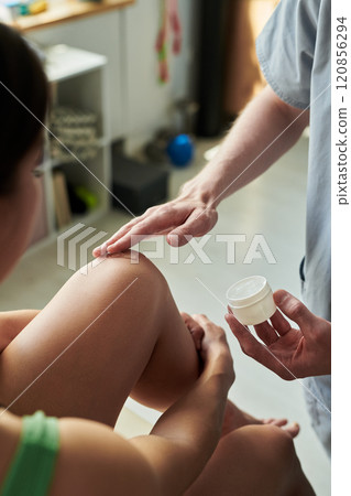 Applying Cream on Patient's Knee in Medical Setting Applying Cream on Patient's Knee in Medical Setting 120856294
