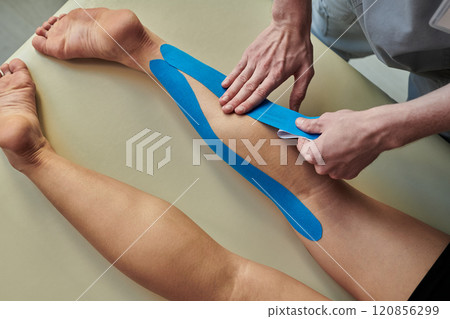 Applying Kinesiology Tape on Patient's Leg in Clinic 120856299