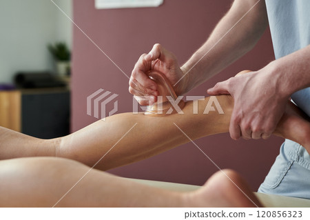 Performing Cupping Therapy on Client's Calf 120856323