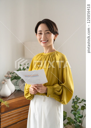 A woman standing indoors with documents 120856418