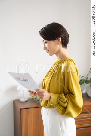 一名婦女拿著文件站在室內 120856430