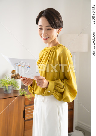 一名婦女拿著文件站在室內 一名婦女拿著文件站在室內 120856432