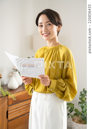 一名婦女拿著文件站在室內 120856435