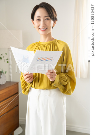 A woman standing indoors with documents 120856437